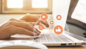 Hands typing on a laptop with floating icons for email, likes, and engagement—representing email marketing and digital outreach tools available to Chamber members