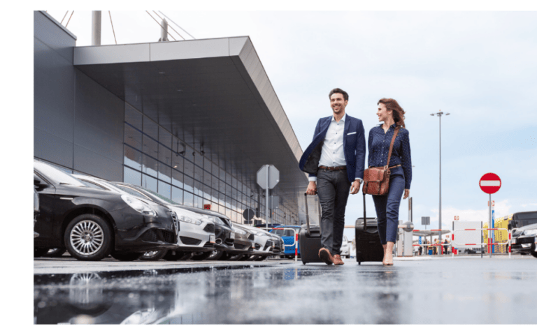 Business travelers walking with luggage through an airport parking lot, representing exclusive Chamber member discounts on airport and business travel parking